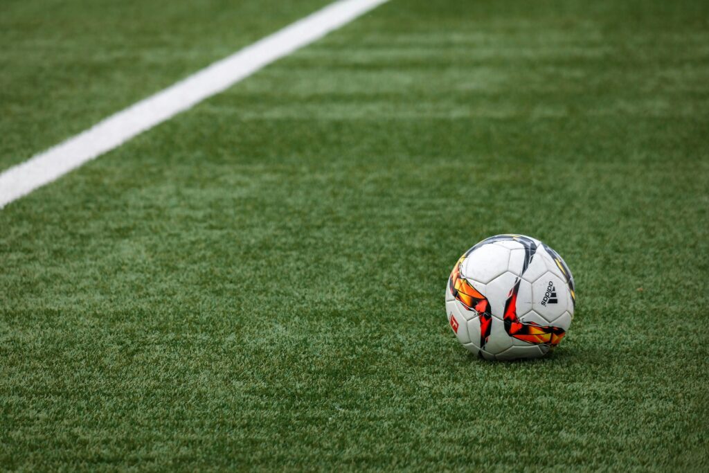 pexels-photo-274506-274506 A vibrant soccer ball resting on a pristine grass field beside a white sideline.